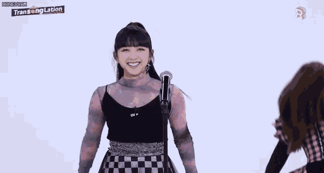 a girl is holding a microphone and smiling while another girl looks on ..