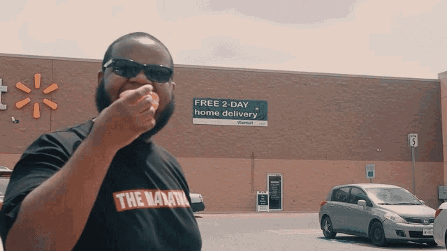 a man standing in front of a walmart store with a free 2 day home delivery sign behind him