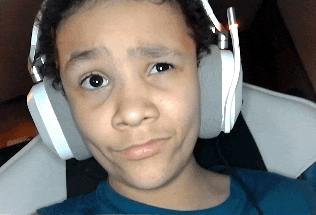 a young boy wearing white headphones looks at the camera