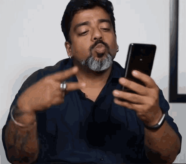 a man with a beard is pointing at his phone