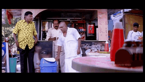 a man in a yellow shirt is standing in front of a coca cola machine