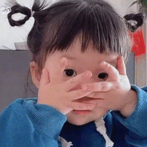 a little girl is making a face with her hands and making a funny face .