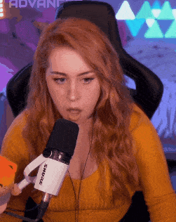 a woman is sitting in front of a shure microphone and holding a card