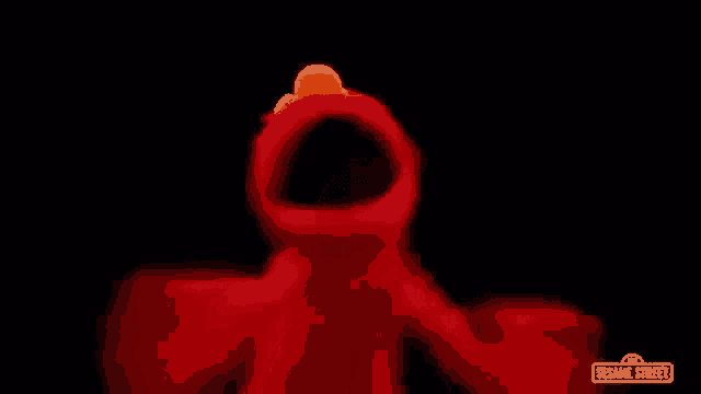 elmo from sesame street is dancing in the dark with a black background .