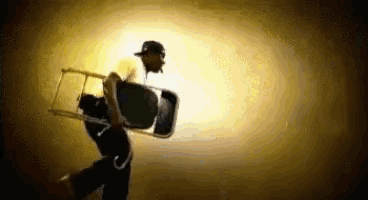 a man in a hat is carrying a chair on his back .