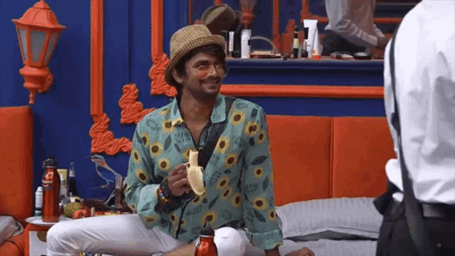 a man sitting on a bed with a banana in his hand