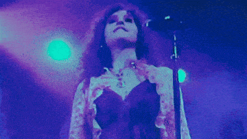 a woman is singing into a microphone on stage in front of a crowd