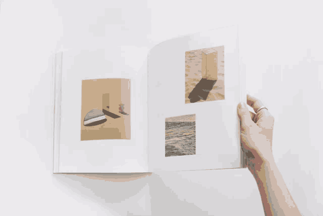 a hand with a ring on it is holding a book open to a page with a picture of a mirror on it