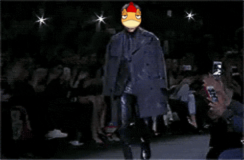 a man in a suit with a chicken face on his head walks down the runway at a fashion show