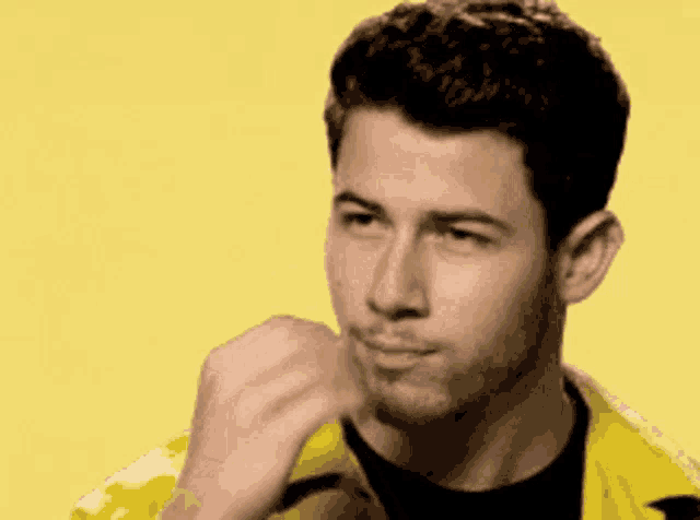 a close up of a man 's face with his hand on his chin on a yellow background