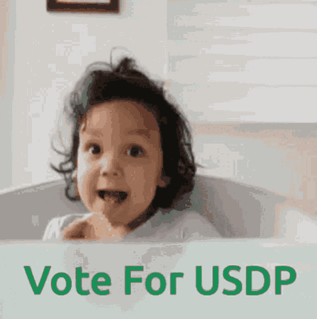 a little girl with a sign that says vote for usdp
