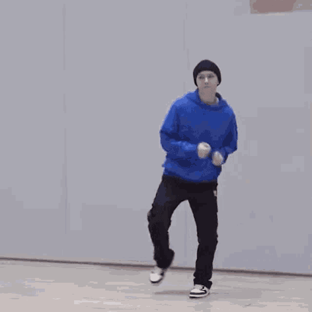 a man in a blue hoodie and black pants is dancing on a dance floor .