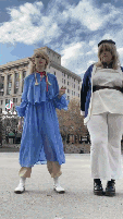 two women standing next to each other in front of a building .