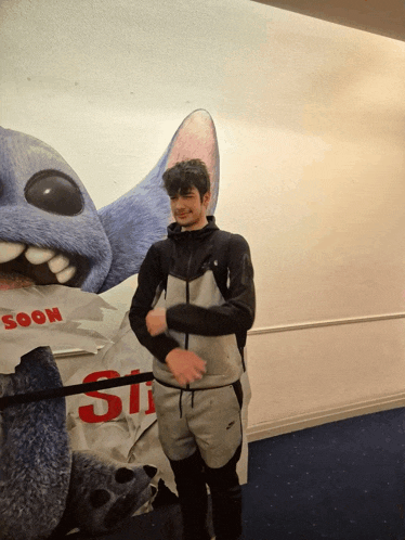 a man stands in front of a stitch poster that says soon