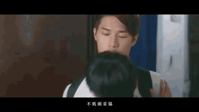 a man is kissing another man on the forehead .