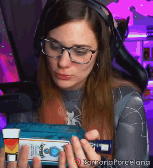 a woman wearing glasses and headphones is holding a shot glass and a bottle of jim beam