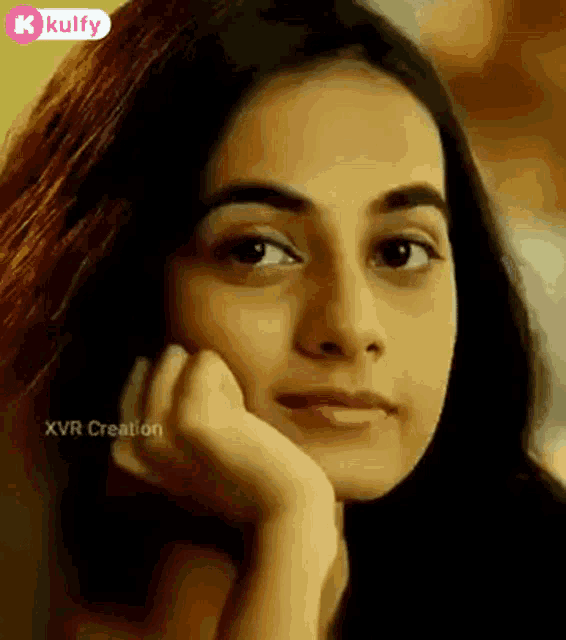 a close up of a woman with her hand on her chin .
