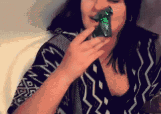 a woman wearing a black and white shirt is eating a green candy