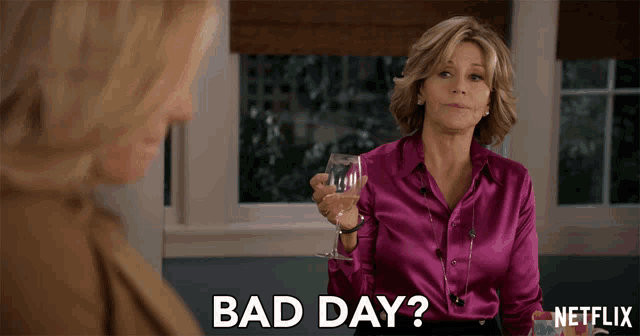 a woman in a purple shirt is holding a glass of wine and the words bad day are above her