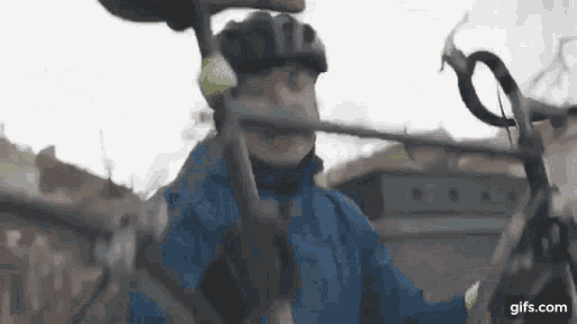 a man in a blue jacket and helmet is riding a bike .