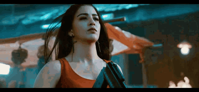 a woman is holding a gun in her hand in a dark room .