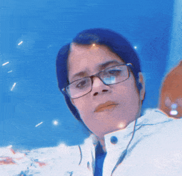 a woman wearing glasses and headphones looks at the camera with a blue background