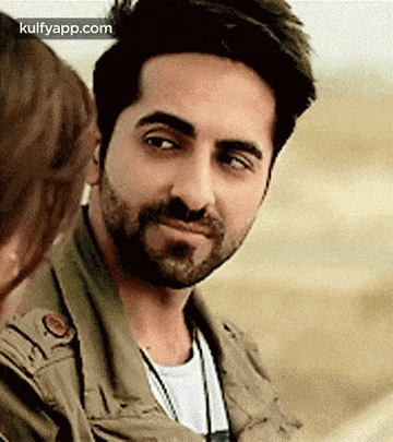a man with a beard is smiling while looking at a woman .