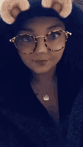 a woman wearing glasses and a furry hat looks at the camera