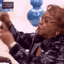 a woman wearing glasses is sitting on a couch talking on a phone .