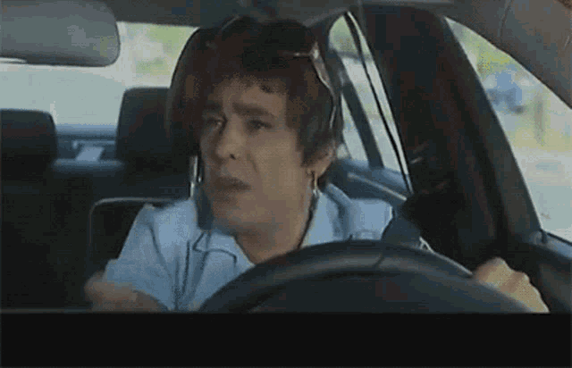 a woman with red hair is driving a car with a headset on