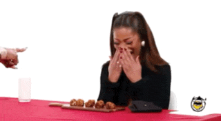 a woman is laughing while sitting at a table with a tray of food on it