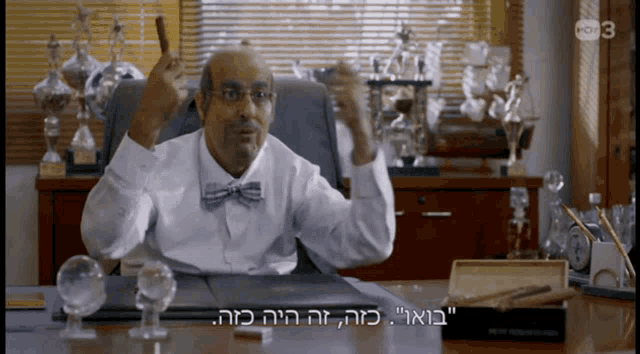 a man in a bow tie is sitting at a desk with the number 3 on the bottom