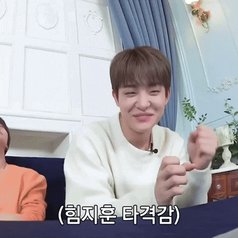 a man in a white sweater is making a funny face in a room with chinese writing on the wall behind him