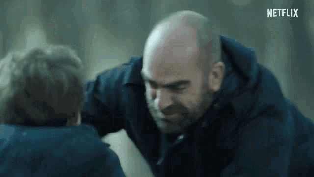 a bald man with a beard is talking to a young boy in a netflix trailer .