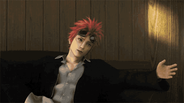 a man with red hair is laying on a wooden couch