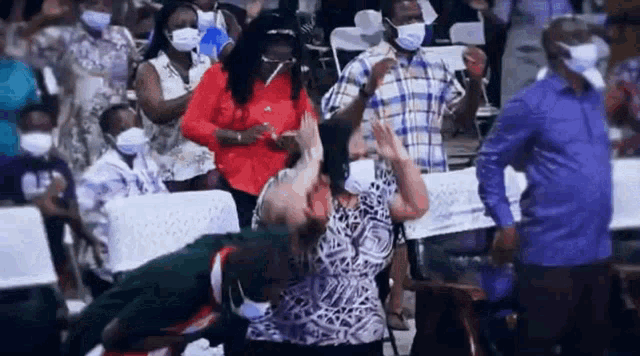 a group of people wearing face masks are sitting in a crowd .
