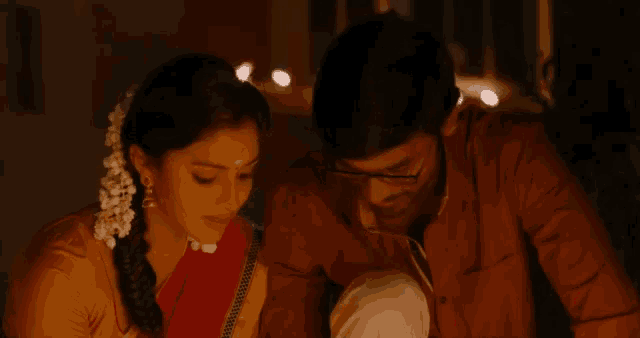 a man and a woman are looking at each other with candles in the background