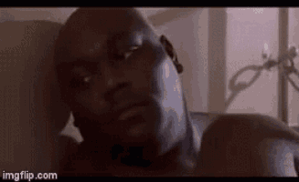 a close up of a man laying on a bed looking at the camera .