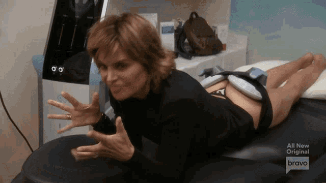 a woman laying on a table with a bravo logo on the bottom right