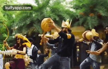 a group of people are dancing in a park in front of trees .