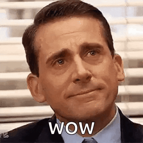 a man in a suit and tie is making a surprised face with the word wow on his face .