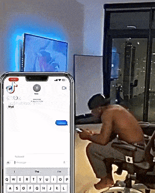 a shirtless man sits in a chair next to a phone that says ' wyd ' on the screen