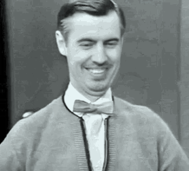 a man wearing a bow tie and a sweater is smiling .