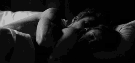 a black and white photo of a man and a woman sleeping in a bed .