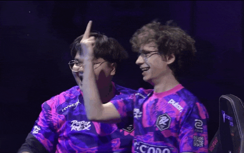 two men wearing purple and pink shirts with hyperx on the front