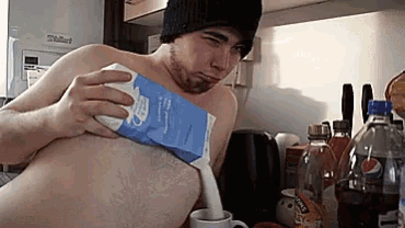 a man without a shirt is pouring milk from a carton