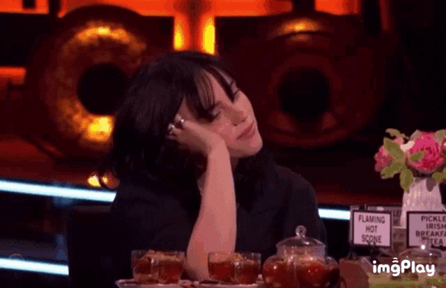 a woman sits at a table with a sign that says flaming hot scoop