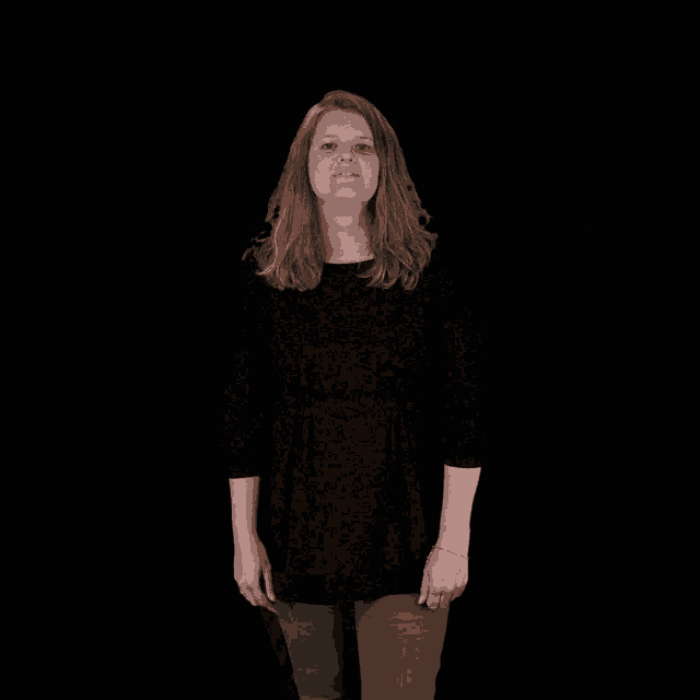 a woman in a black shirt is smiling and raising her arms in the air