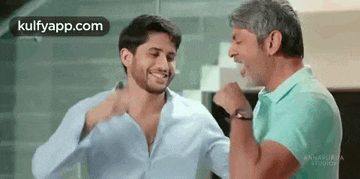 two men are laughing and hugging each other in a room .