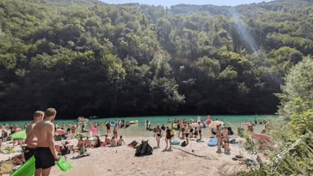 a group of people are gathered on a beach near a body of water